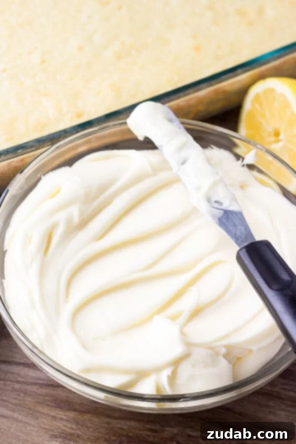 Zesty Lemon Cake with Lemon Cream Cheese Frosting 4 A glistening glass bowl filled with vibrant yellow lemon cream cheese frosting, ready to be spread.