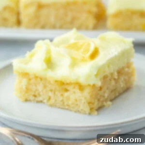 Zesty Lemon Cake with Lemon Cream Cheese Frosting 8 A square slice of incredibly moist lemon cake, richly topped with bright lemon cream cheese frosting and garnished with a thin slice of fresh lemon.