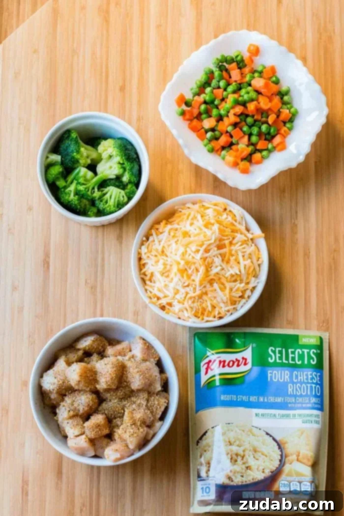 Simple Ingredients for Cheesy Chicken and Rice Casserole: Knorr Selects, chicken, broccoli, peas, carrots, and Colby Jack cheese. An overhead shot showcasing all the fresh and simple ingredients laid out to make the Cheesy Chicken and Rice Casserole, featuring Knorr Selects Four Cheese Risotto.