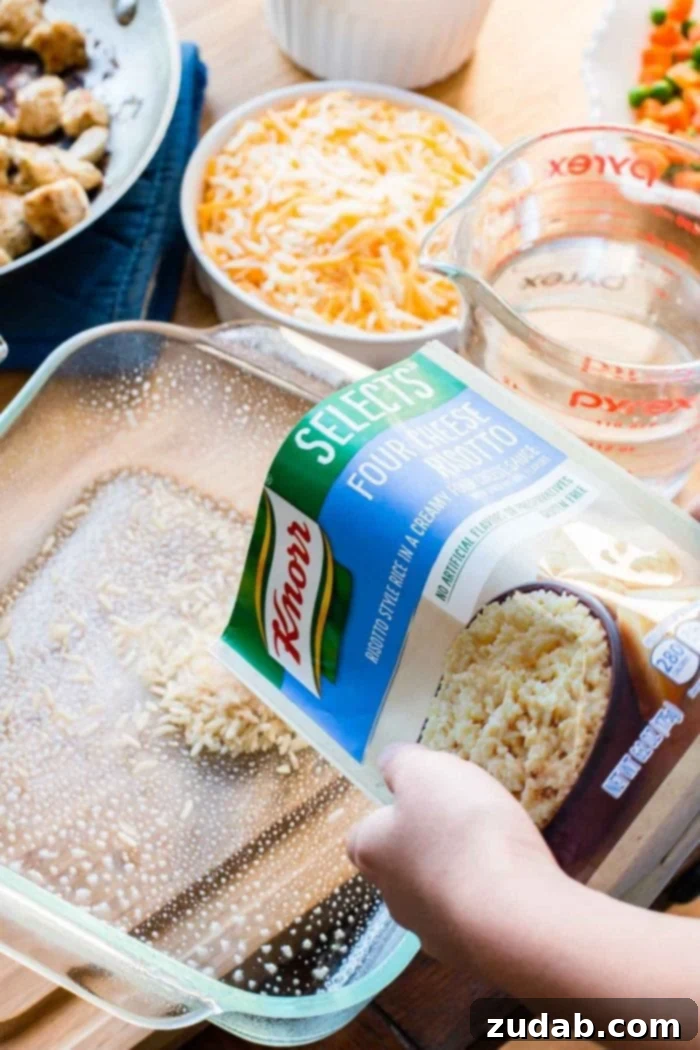 Preparing the Cheesy Chicken and Rice Casserole: Adding Knorr Selects for a flavorful, simple foundation. Hands carefully pouring Knorr Selects Four Cheese Risotto into a greased baking dish, initiating the quick and easy casserole assembly.