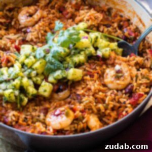 One Pot Sticky Honey Lime Shrimp with Pineapple Chimichurri is a quick and flavorful 20-minute meal with spicy Mexican rice, peppers, beans, and shrimp, topped with honey lime sauce and fresh chimichurri.