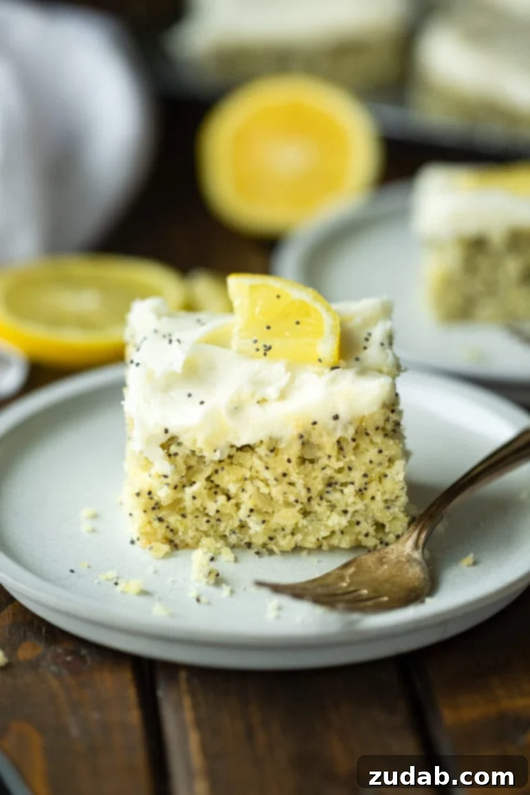 a photo of a piece of lemon poppy seed cake topped with a white cream cheese frosting and small lemon slice