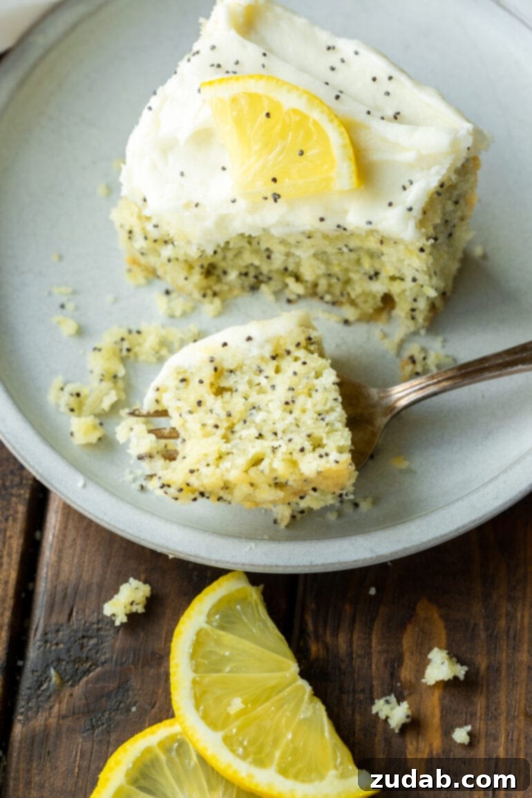 a photo of a bite of lemon poppy seed cake on a fork and sitting next to a slice of cake