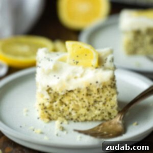 a photo of a piece of lemon poppy seed cake topped with a white cream cheese frosting and small lemon slice