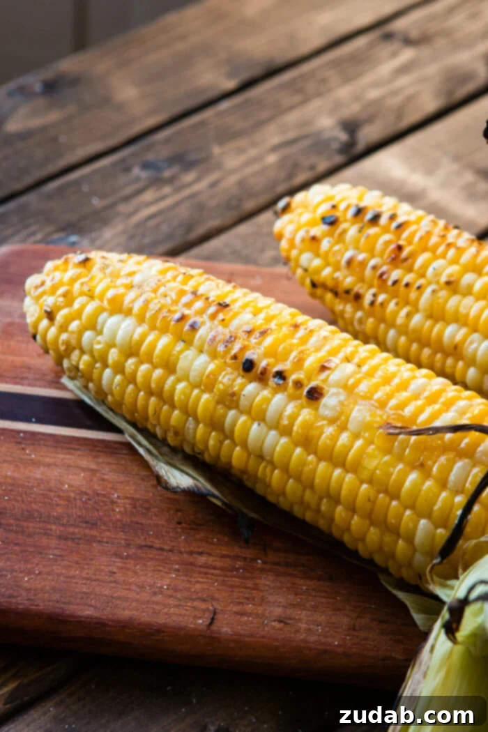 Discover the ultimate methods for grilling succulent, flavorful corn on the cob. Two ears of perfectly grilled corn on a rustic cutting board, ready to be seasoned.