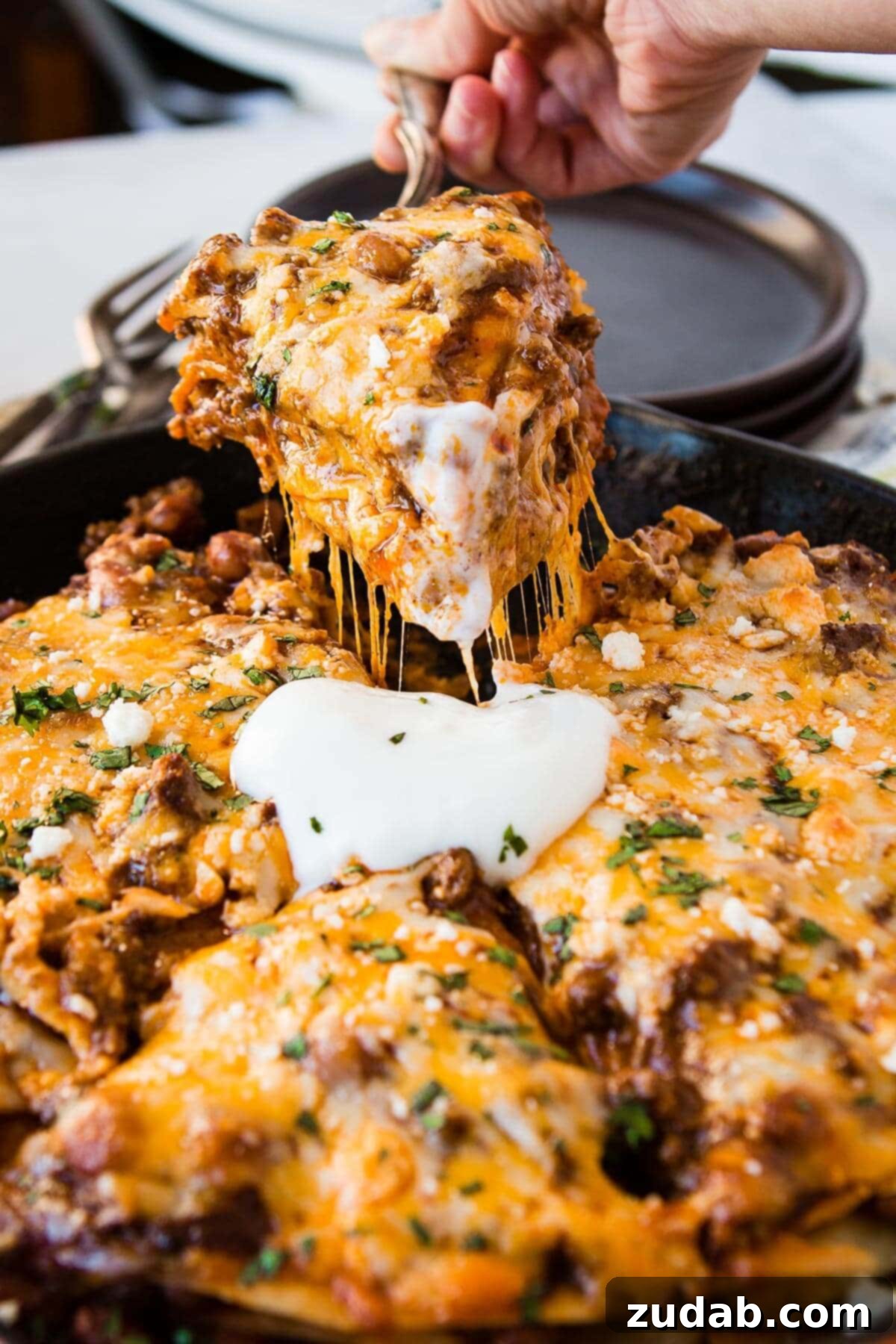One Pan Cheesy Beef Enchilada Bake 11 a photo of a slice of ground beef enchilada casserole being removed from a cast iron skillet