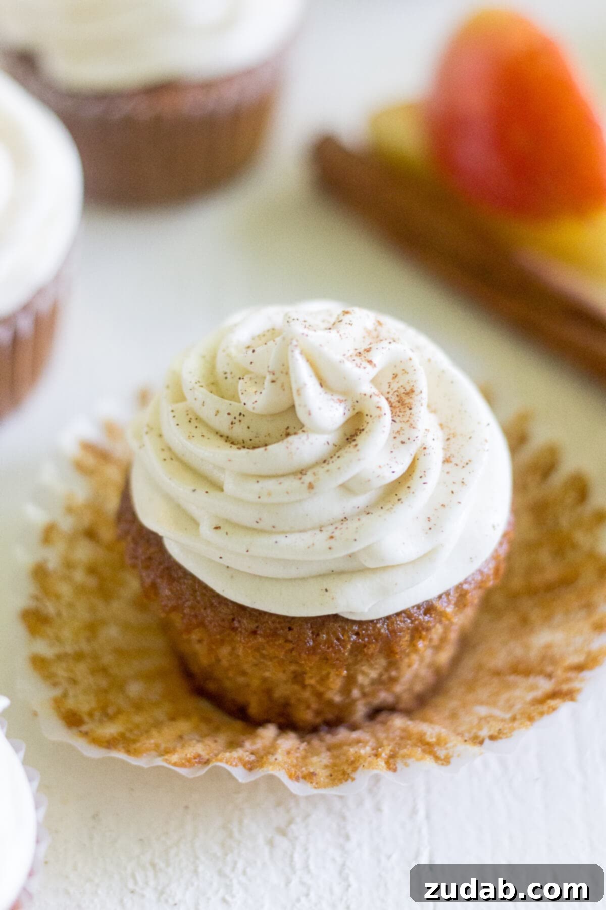 Warm Apple Cider Cupcakes with Spiced Cream Cheese Frosting 4 an apple cider cupcake frosted with a swirl of cream cheese frosting. the cupcake liner has been pulled down