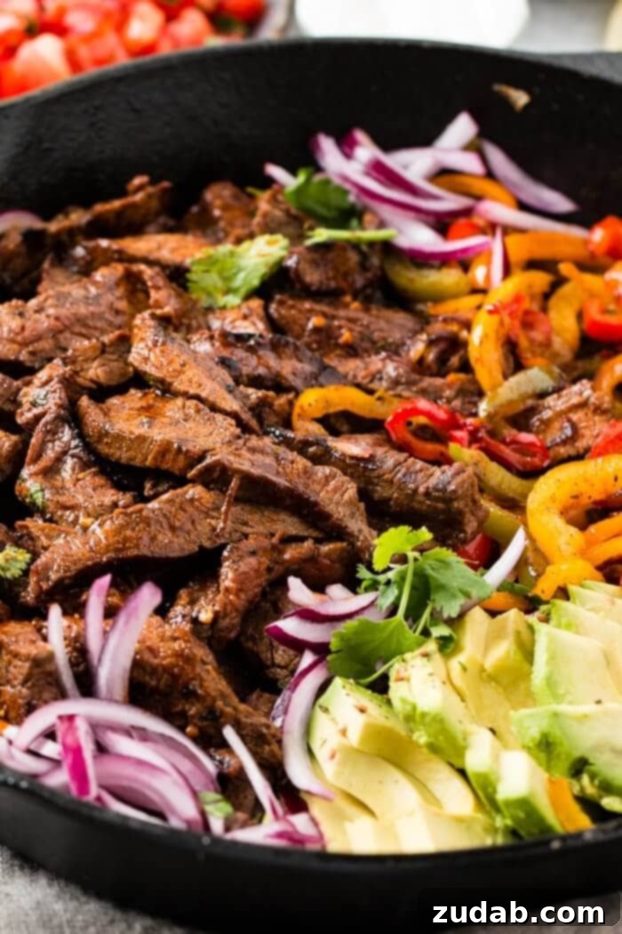 Our Secret Marinade for Tender Steak Fajitas 2 Sizzling steak fajitas with colorful bell peppers and onions in a cast iron skillet, ready to be served