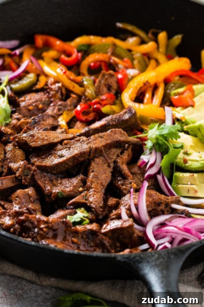 Our Secret Marinade for Tender Steak Fajitas 3 Another view of steak fajitas with vibrant peppers and onions in a cast iron skillet, emphasizing the fresh ingredients