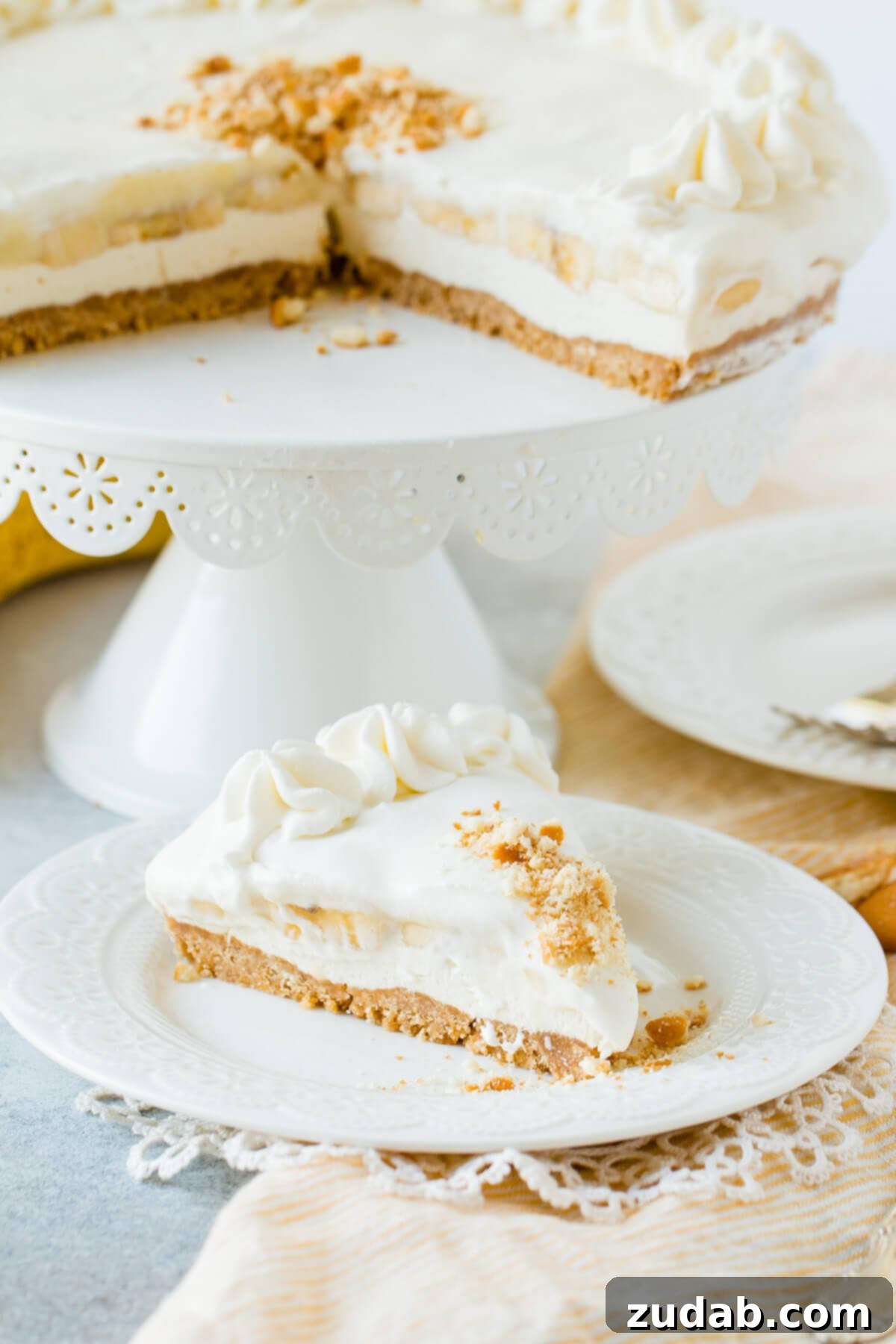 Dreamy No-Bake Banana Pudding Cheesecake 3 slice of banana pudding cheesecake on plate in front of cake stand