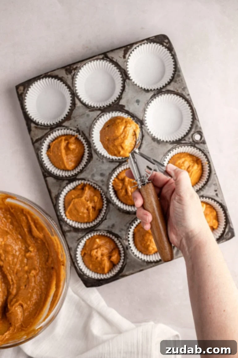 Heavenly White Chocolate Pumpkin Muffins 3 Overhead view of pumpkin muffin batter scooped into a muffin tin, ready for baking. Shows consistency and preparation.