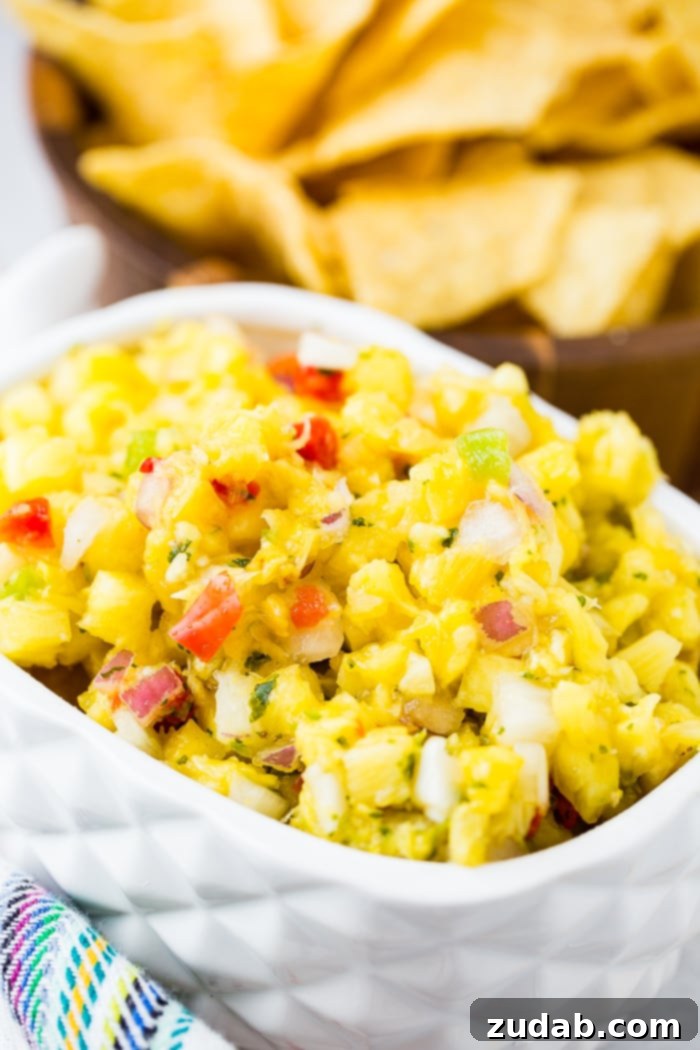 Ultimate Pineapple Salsa 2 A crisp white dish brimming with fresh pineapple salsa, featuring bright diced pineapple, colorful bell peppers, vibrant cilantro, and finely chopped red onions.