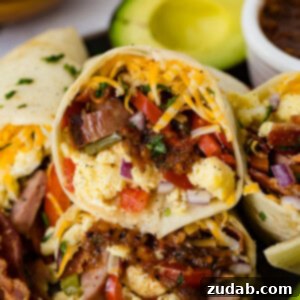 Two apple chicken sausage burritos on a plate with salsa and avocado