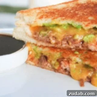 The BBQ Pork Guac Melt 4 Close-up of a skillet-fried BBQ Pulled Pork Grilled Cheese, showing melted cheese and filling