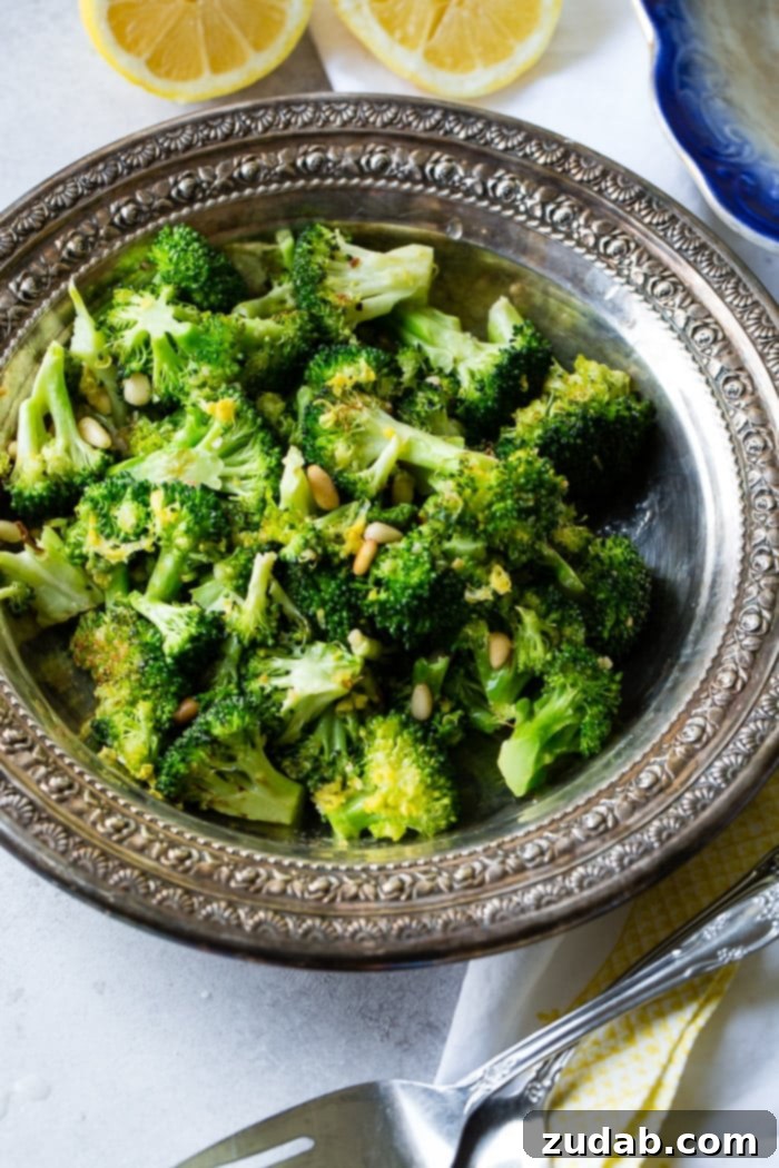 Bright Lemon Roasted Broccoli 3 A second shot of a vintage silver bowl presenting perfectly lemon roasted broccoli with golden pine nuts and white Parmesan flakes, showcasing its enticing texture.