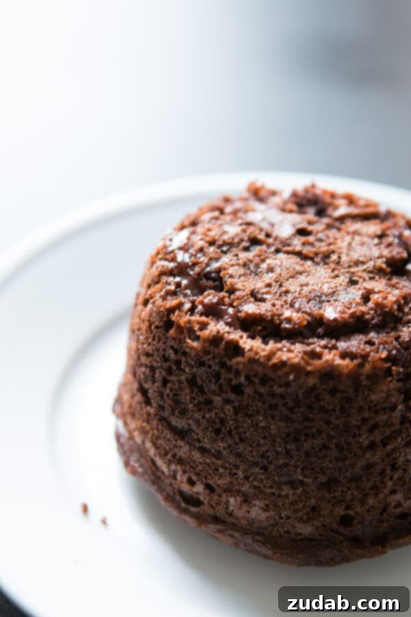 Copycat Chili's molten lava cakes recipe is way easier to make than you probably think and that hot fudge oozing out is such a crowd pleaser! Ingredients laid out for homemade molten lava cakes, including boxed cake mix, eggs, milk, oil, sour cream, hot fudge, and chocolate chips for magic shell.