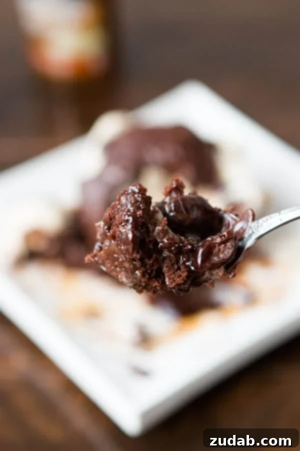 Copycat Chili's molten lava cakes recipe is way easier to make than you probably think and that hot fudge oozing out is such a crowd pleaser! Two molten lava cakes with chocolate oozing out, topped with vanilla ice cream and a drizzle of caramel, ready to be enjoyed.