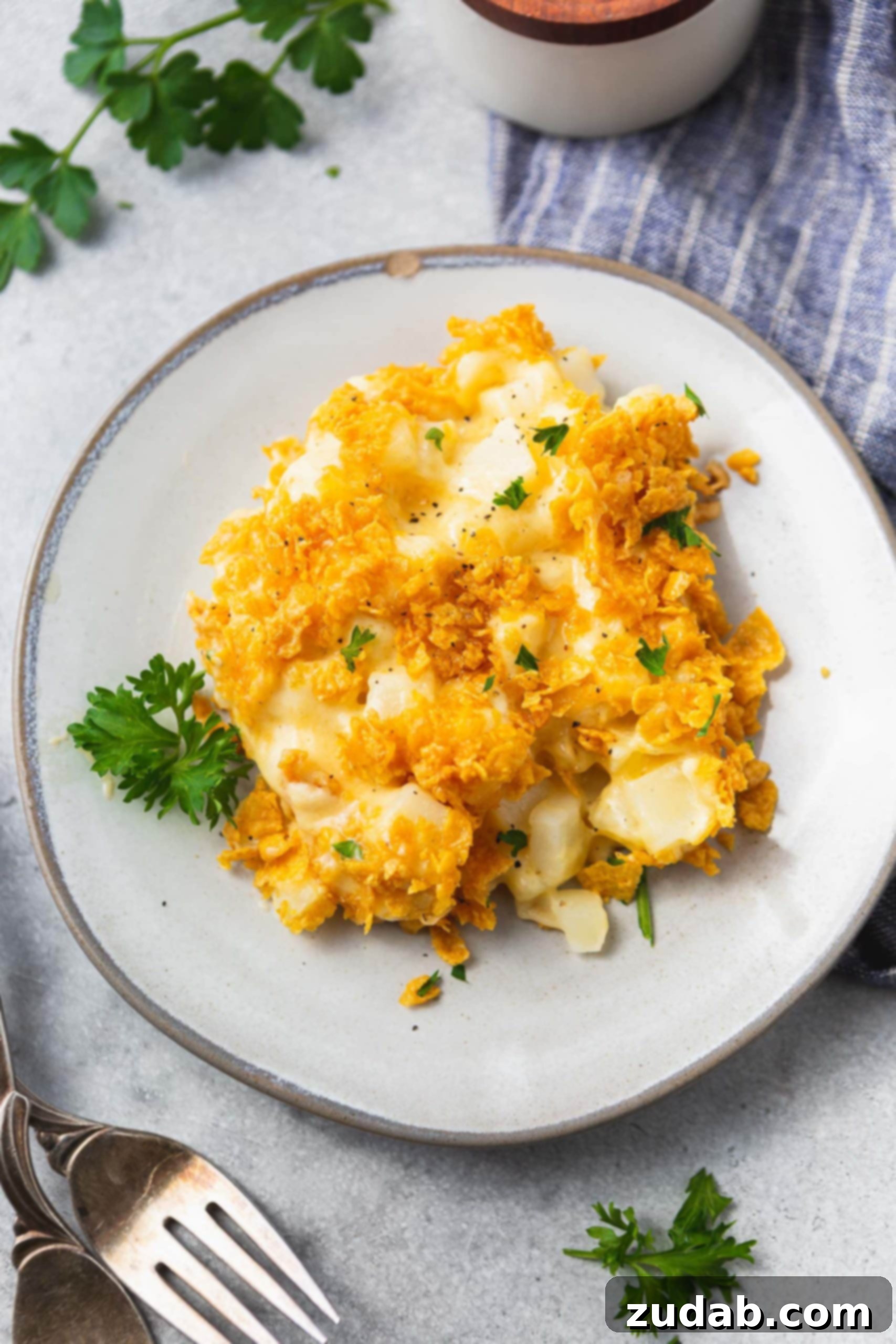 Funeral Potatoes Cheesy Potato Casserole A photo of a plate of cheesy potato casserole topped with golden crunchy topping, ready to be enjoyed.