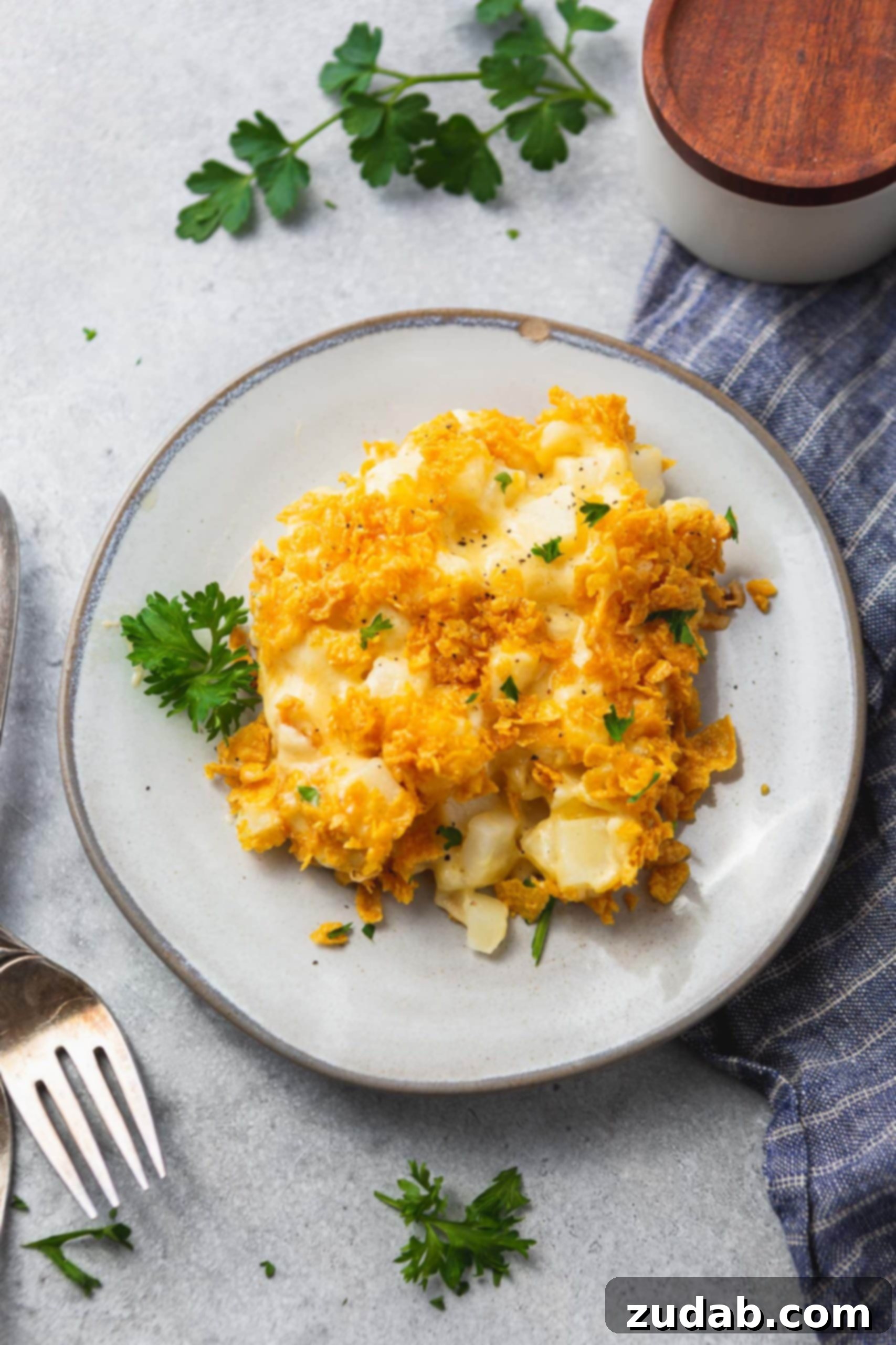 Funeral Potatoes Cheesy Potato Casserole A photo of a plate of cheesy potato casserole topped with golden crunchy topping, ready to be enjoyed.