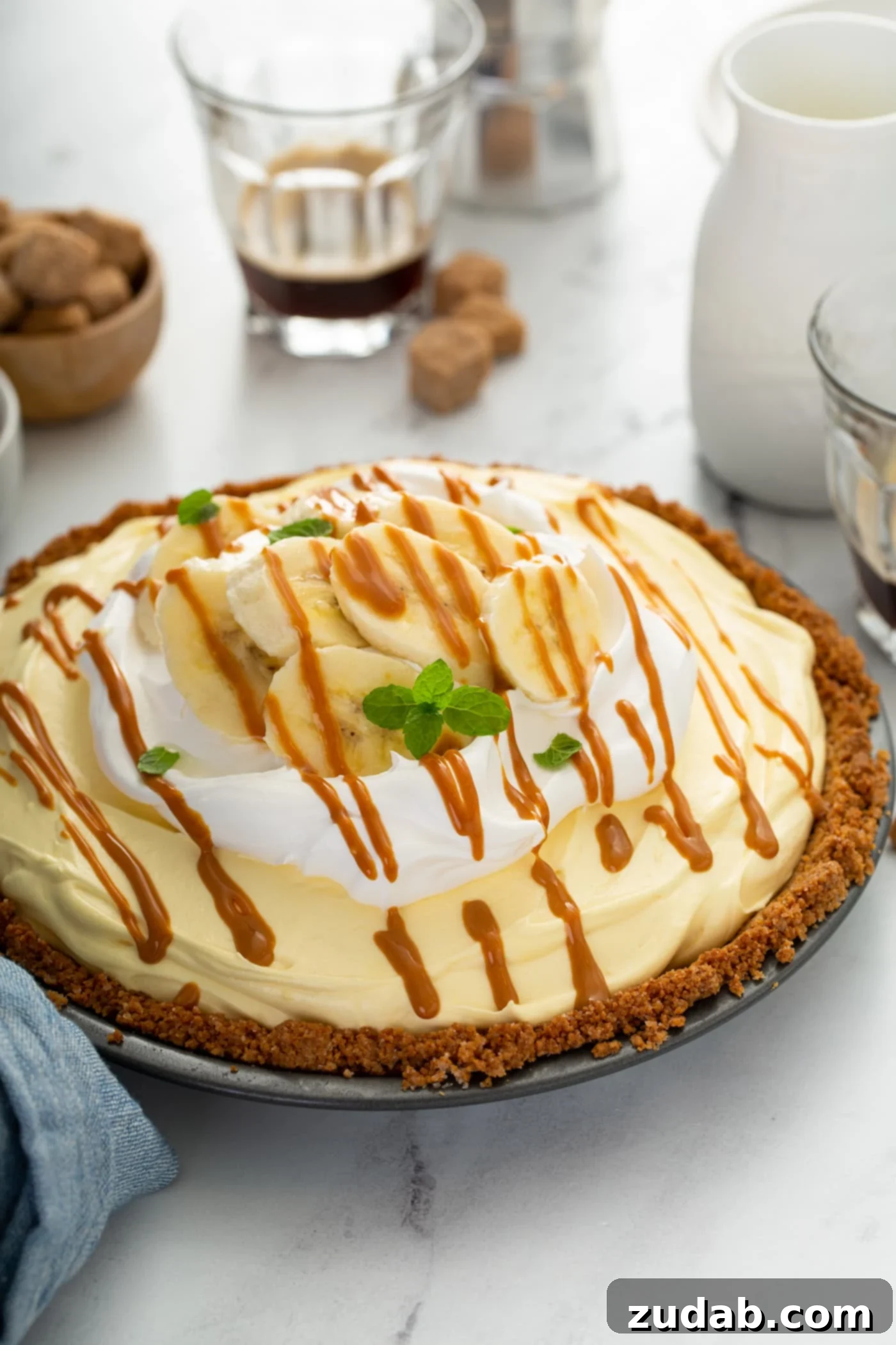 Decadent Dulce De Leche Banana Cream Pie 2 A dulce de leche banana cream pie in a graham cracker crust. the pie is topped with whipped cream and drizzled with dulce de leche.