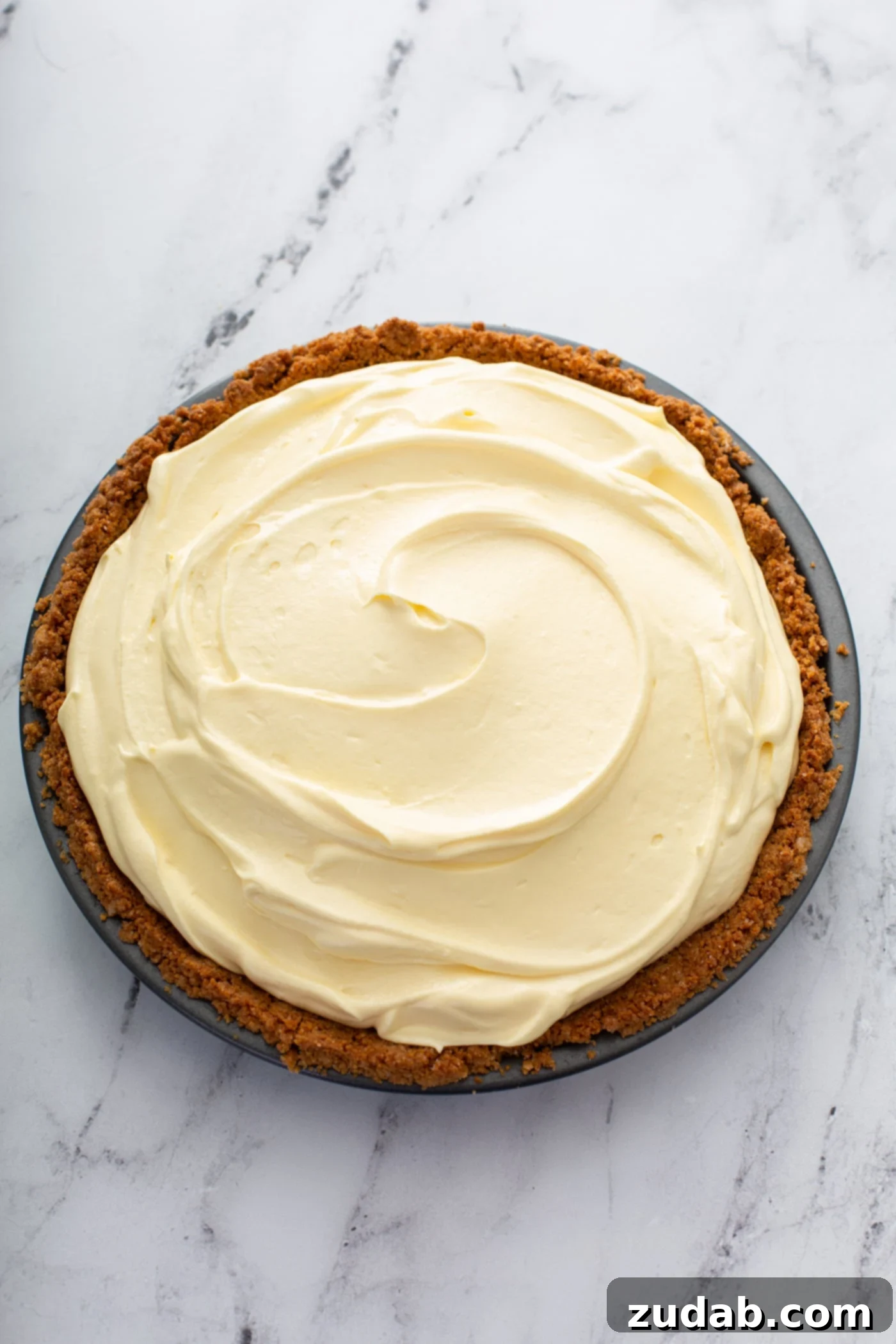 Decadent Dulce De Leche Banana Cream Pie 17 A dulce de leche banana cream pie in a graham cracker crust. The filling is light yellow and the crust is a deep graham cracker brown.