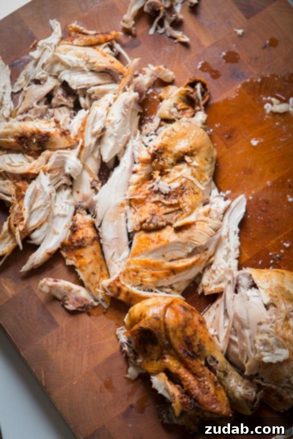 This is the easiest way to enjoy a juicy, rotisserie like chicken by only using a crockpot. Slow cooker whole chicken that anyone can make! insta pot, pressure cooker Shredded Slow Cooker Whole Chicken on a wood cutting board.