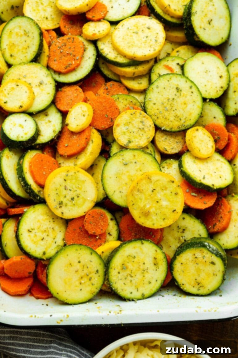 Savory Parmesan Basil Roasted Veggies 4 a photo of a rectangular baking dish filled with fresh sliced zucchini, yellow squash and carrots ready to be roasted
