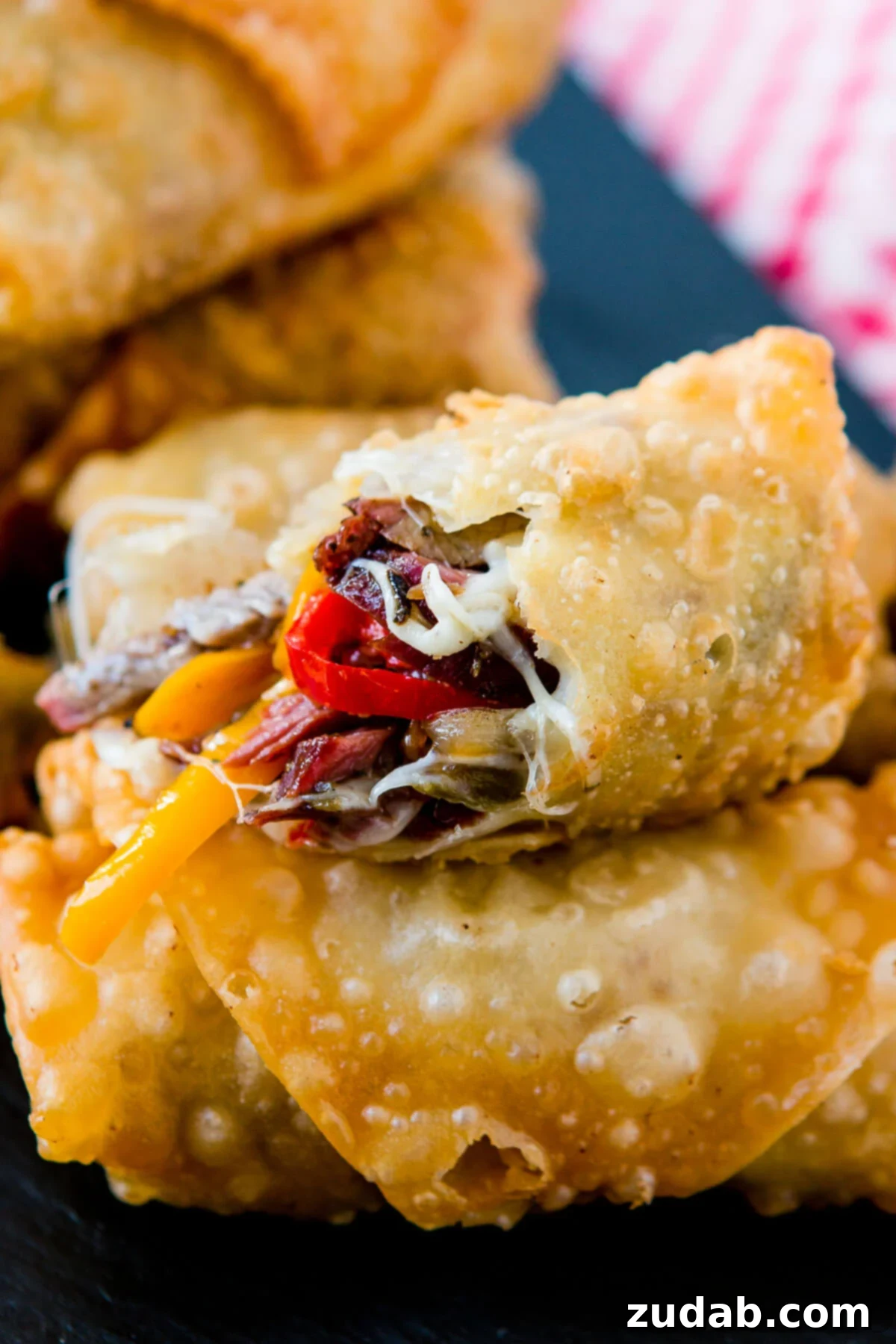 Crispy Philly Cheesesteak Egg Rolls 2 Golden, crispy Philly Cheesesteak Egg Rolls, filled with savory meat and cheese, perfect for football games and parties.
