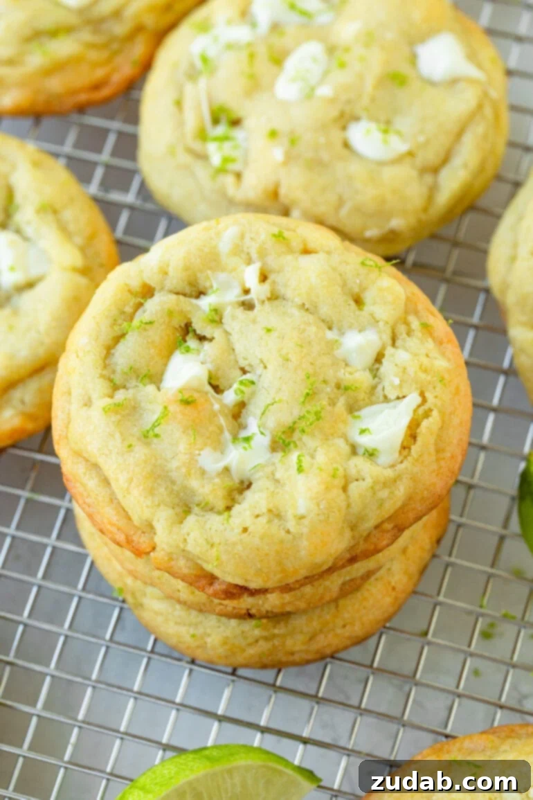 Zesty White Chocolate Key Lime Cookies 3 a photo of a stack of 4 white chocolate lime cookies baked until golden sitting on a wire cooling rack and surrounded by other cookies