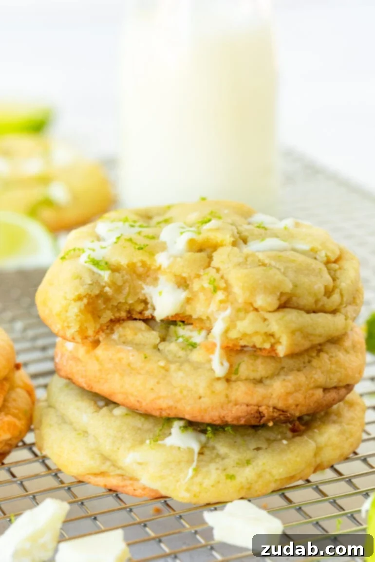 Zesty White Chocolate Key Lime Cookies 4 a photo of a stack of golden baked key lime cookies loaded with white chocolate chunks with a bite taken out of the top cookie