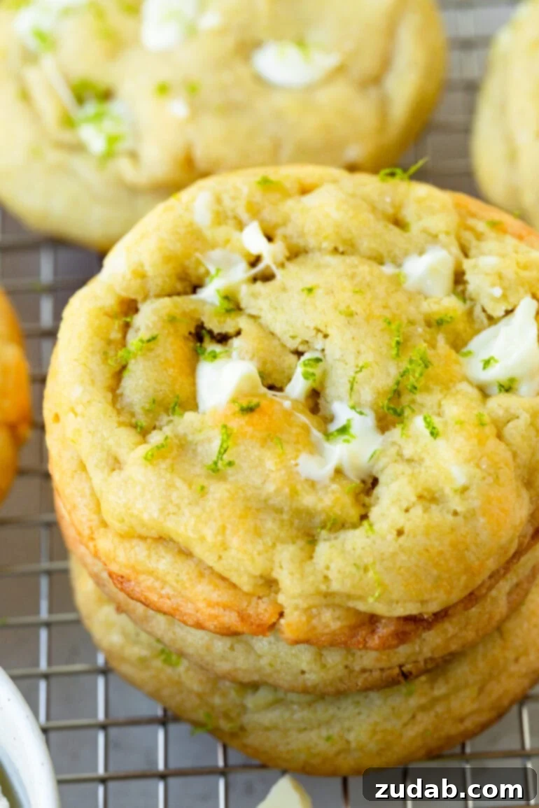 Zesty White Chocolate Key Lime Cookies 8 a close up of a stack of white chocolate lime cookies sitting on a wire cooling rack