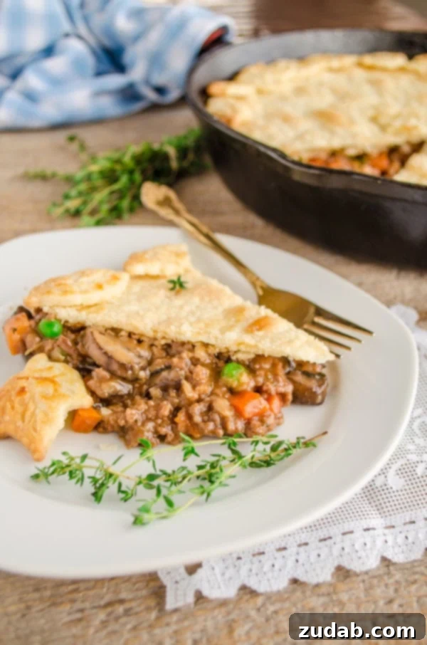 Weeknight Skillet Beef Pot Pie 2 A slice of 30 Minute Skillet Beef Pot Pie sits on a plate garnished with fresh thyme.