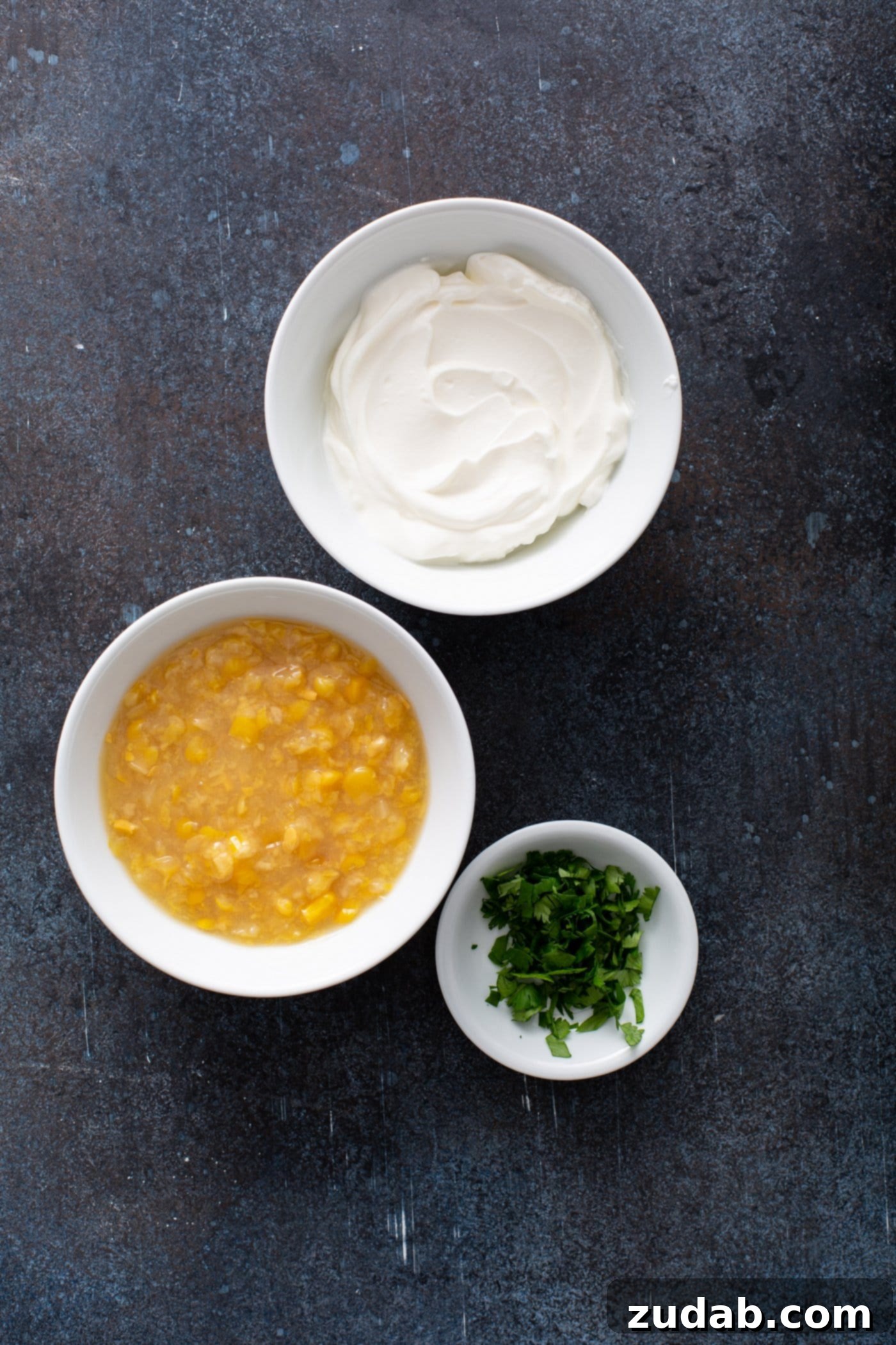 Small bowls of cream corn, cilantro, and sour cream, ready to be combined for the sweet corn crema.