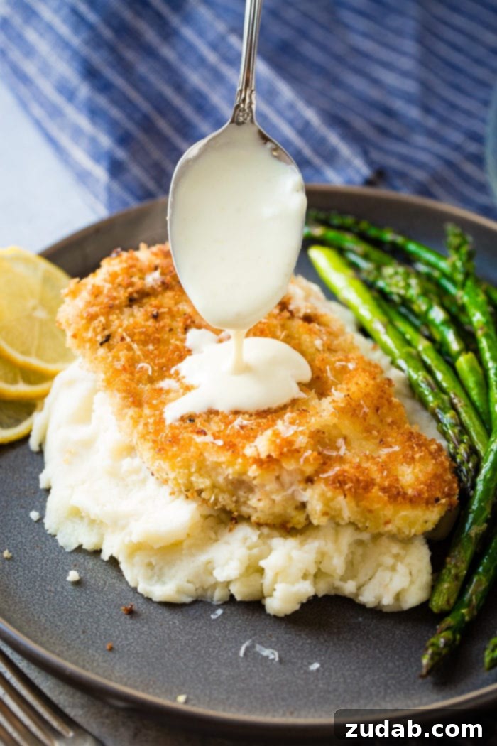 Golden Panko Chicken with Bright Lemon Cream 3 lemon cream sauce being drizzled over panko chicken that's laying on mashed potatoes