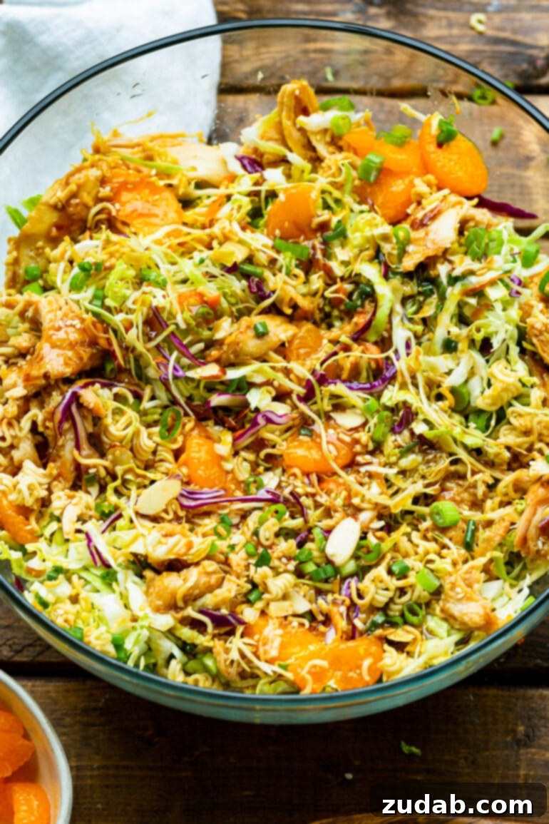 a photo of ramen chinese chicken salad including shredded cabbage, carrots, mandarin oranges, sliced almonds, and crunchy ramen noodles.