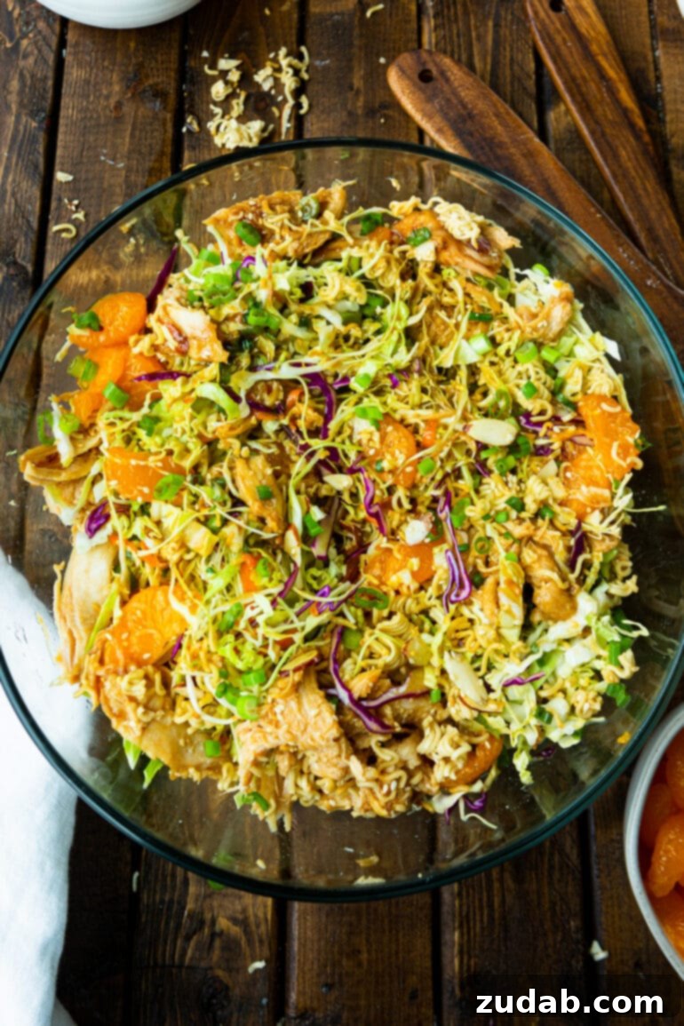 a photo taken over top of a large glass bowl full of oriental chicken salad with ramen noodles.
