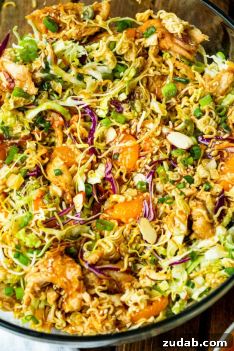 a photo of a bowl of chinese chicken salad including crunchy ramen noodles, red and green cabbage, mandarin oranges, sliced almonds and sesame seeds.