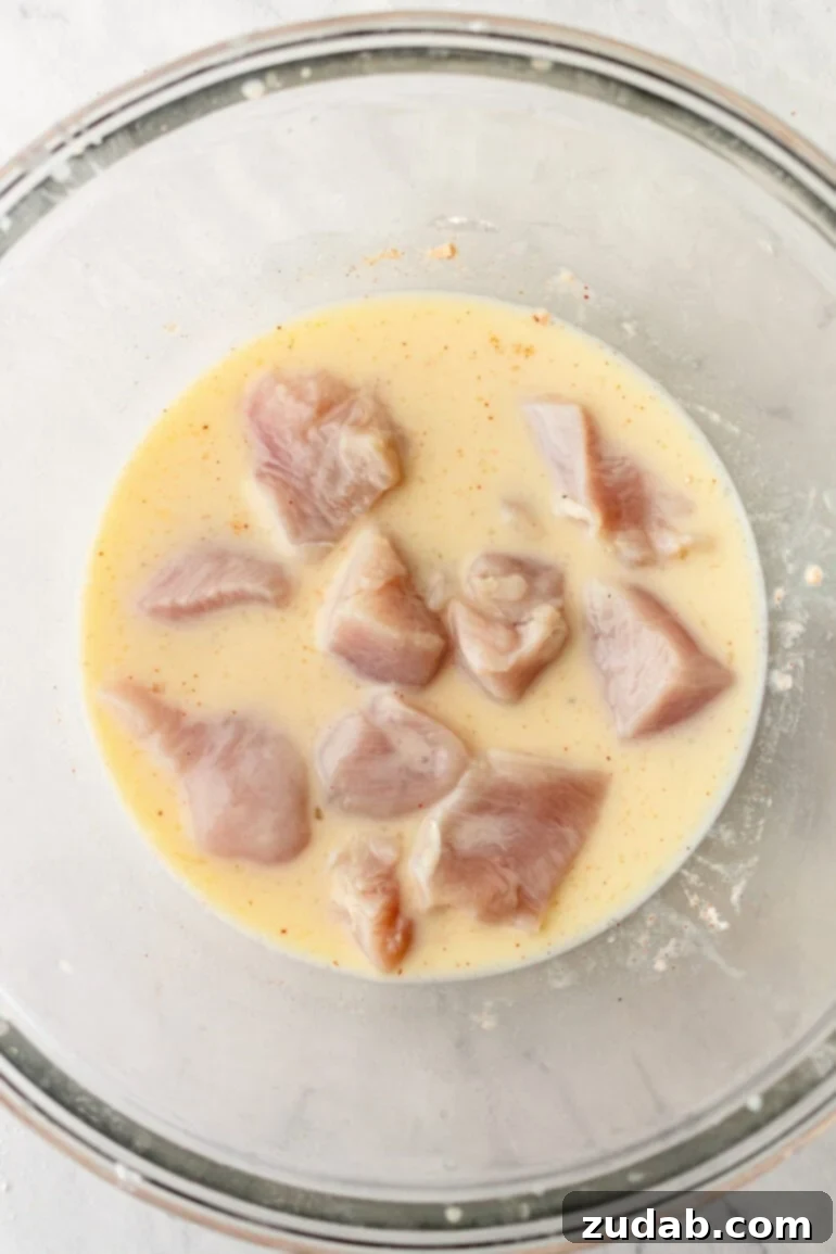 Chicken being dredged in egg mixture