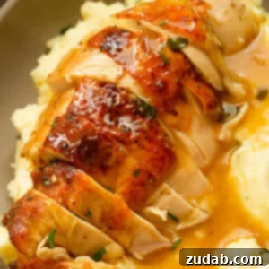 Irresistible Honey Roasted Chicken 11 A photo of a golden roasted chicken breast that has been sliced sitting on tope of mashed potatoes covered in gravy.