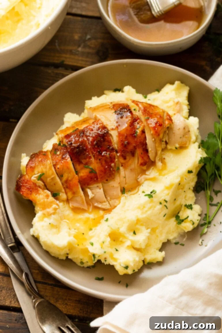 Irresistible Honey Roasted Chicken 3 A beautifully presented golden roasted chicken breast, perfectly sliced, resting on a serving of creamy mashed potatoes generously covered in gravy, ready to be enjoyed.