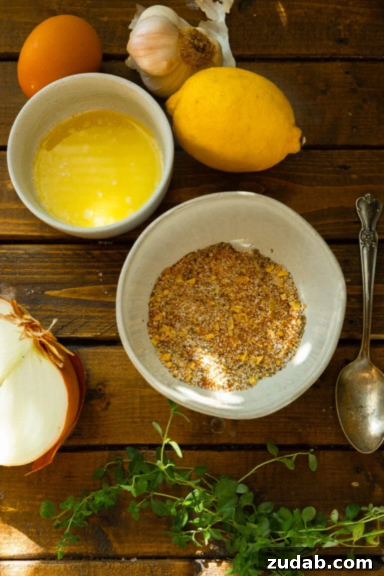 Irresistible Honey Roasted Chicken 4 A collection of fresh ingredients for a whole roasted chicken, neatly arranged in separate small bowls, including a vibrant whole lemon, aromatic seasonings, a half-cut onion, a bowl of melted butter, and fresh herbs.