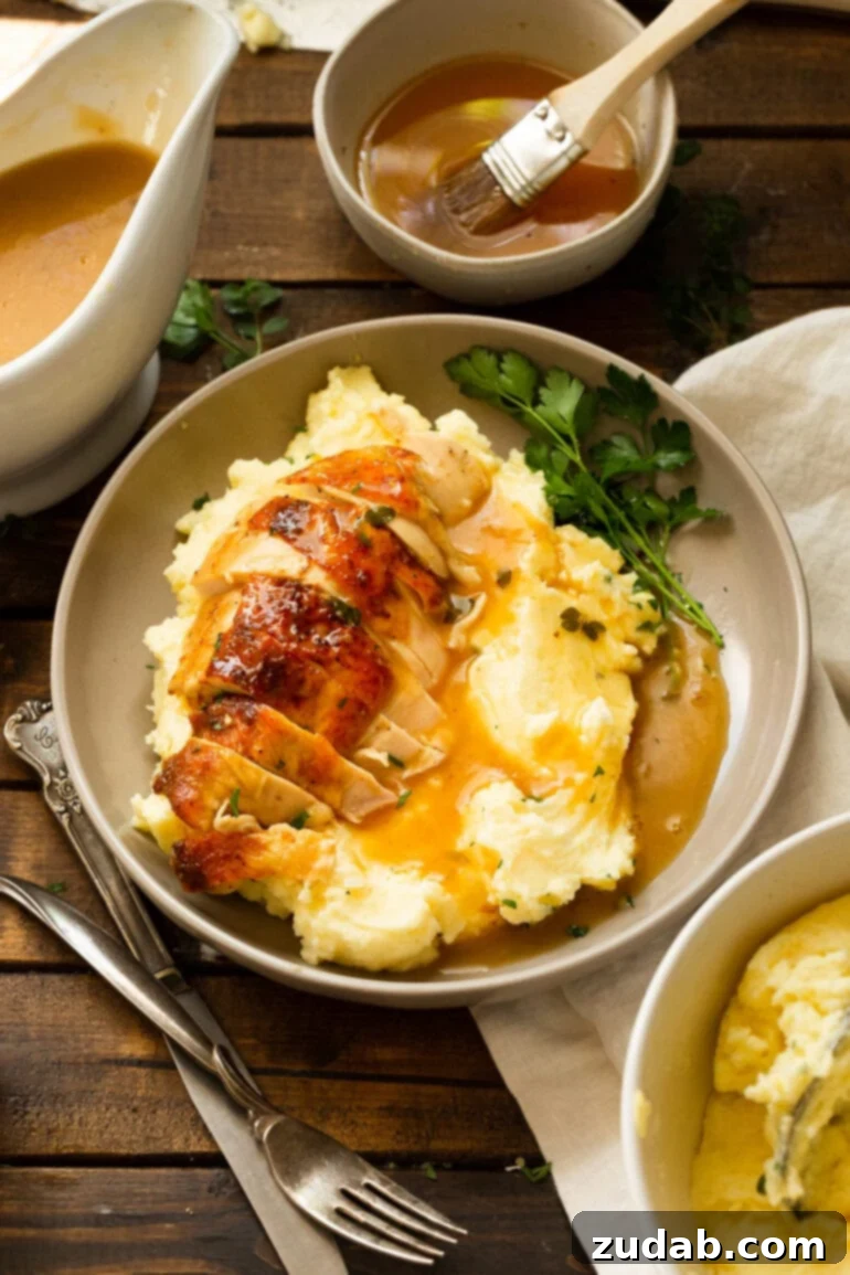 Irresistible Honey Roasted Chicken 6 An overhead view of a dinner plate featuring a hearty serving of mashed potatoes and gravy, elegantly topped with slices of honey roasted chicken breast, garnished with fresh parsley on the side.
