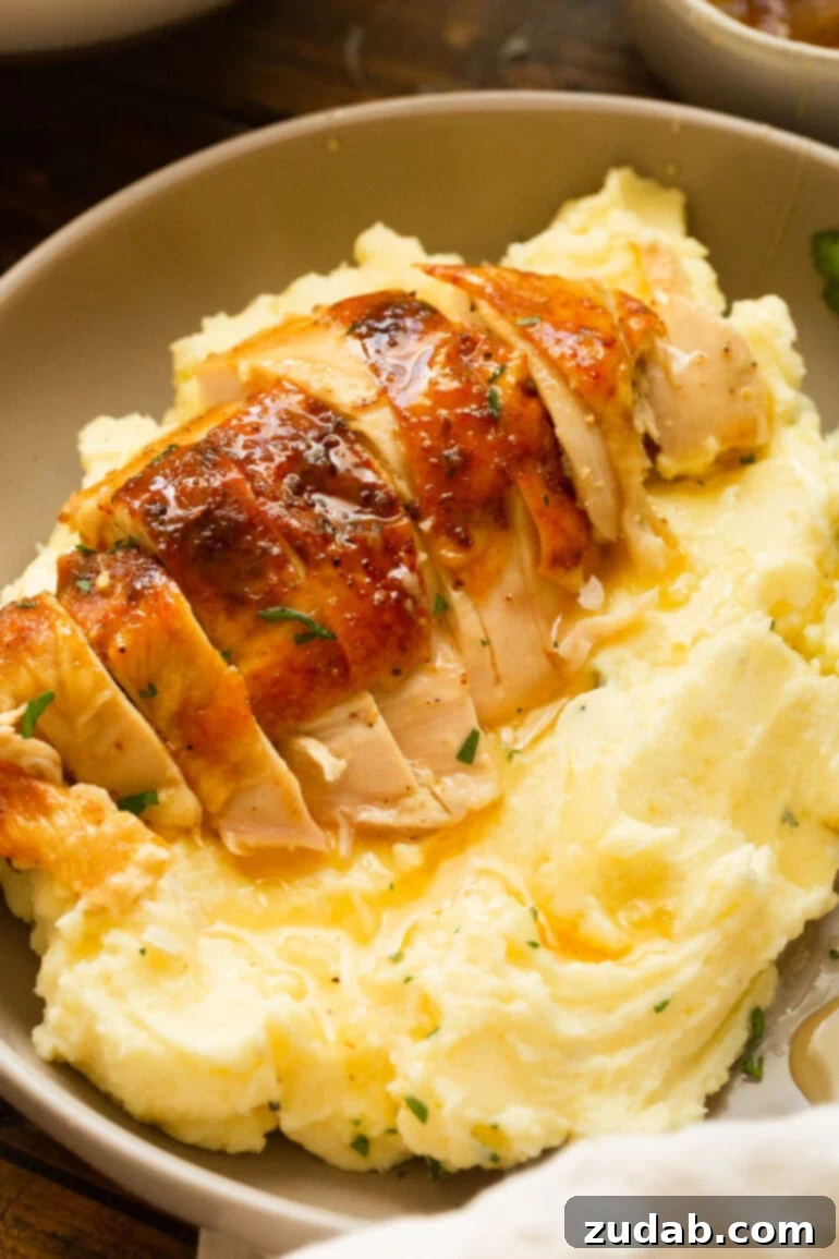 Irresistible Honey Roasted Chicken 9 A golden roasted chicken breast, perfectly sliced, is elegantly placed on a serving of creamy mashed potatoes and rich gravy, highlighting its succulence.