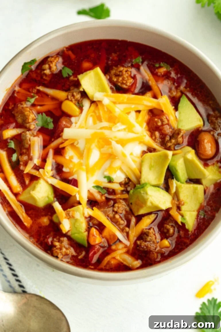 Easy Instant Pot Taco Soup 2 Close-up of Instant Pot taco soup in a grey bowl, garnished with fresh avocado slices, shredded cheddar cheese, a dollop of sour cream, and a sprinkle of fresh cilantro.