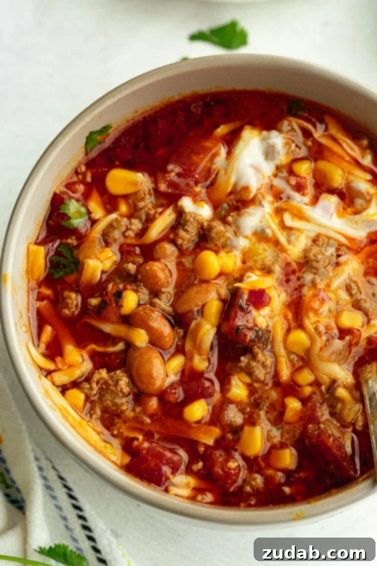 Easy Instant Pot Taco Soup 3 Instant Pot taco soup in a rustic grey bowl, beautifully topped with fresh cilantro, a generous sprinkle of shredded cheese, and a dollop of creamy sour cream.