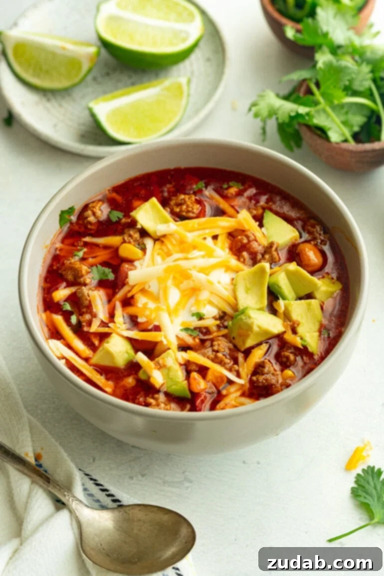 Easy Instant Pot Taco Soup 8 A bowl of Instant Pot taco soup topped with shredded cheddar cheese, sour cream, and diced avocado, ready to be enjoyed.