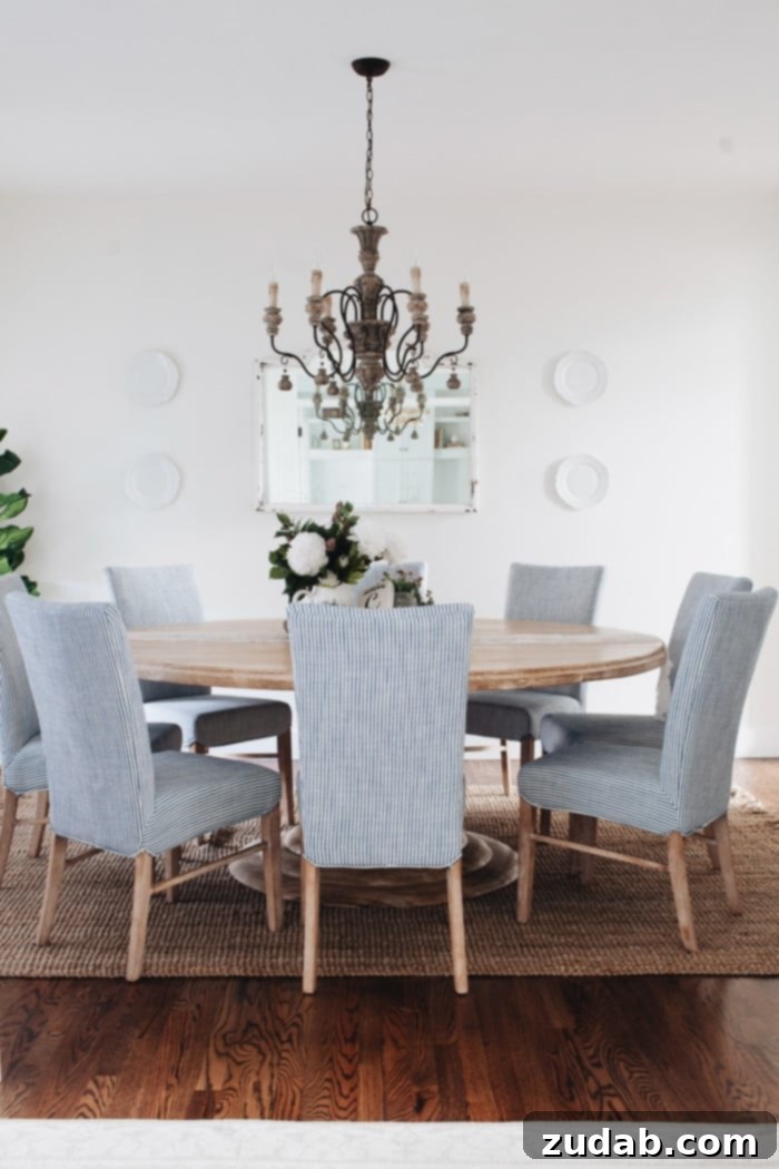 A beautifully transformed French Country Dining Room featuring a round dining table, striped chairs, and an elegant chandelier, embodying a welcoming gathering space.