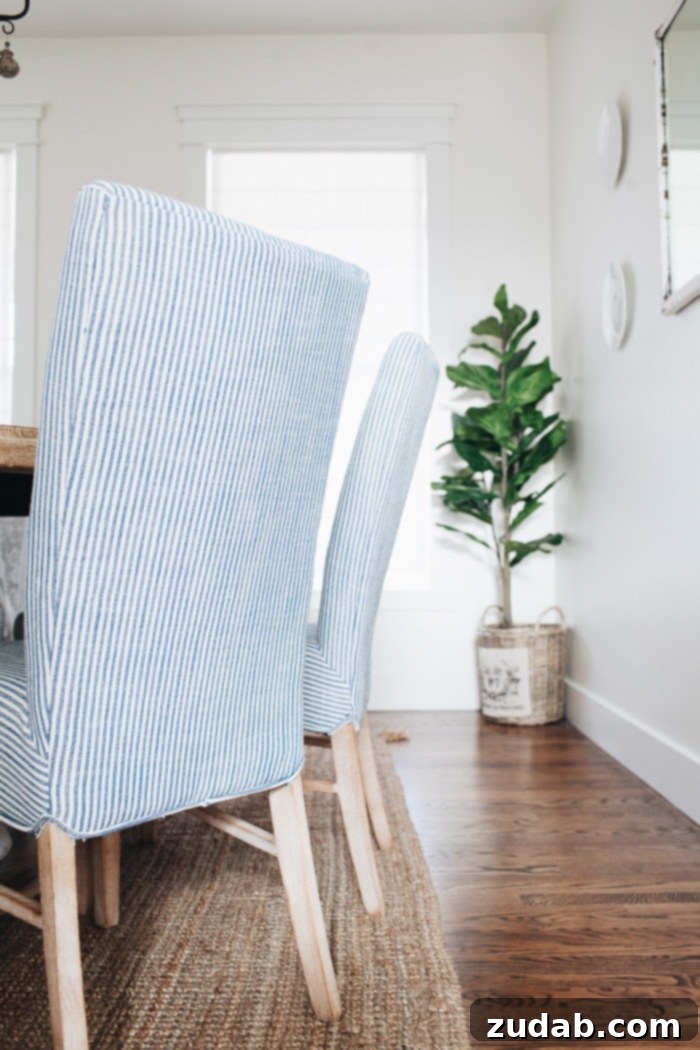 Stylish blue and white striped upholstered Monson chairs with sturdy wood legs, enhancing the French Country dining room's comfort and aesthetic.