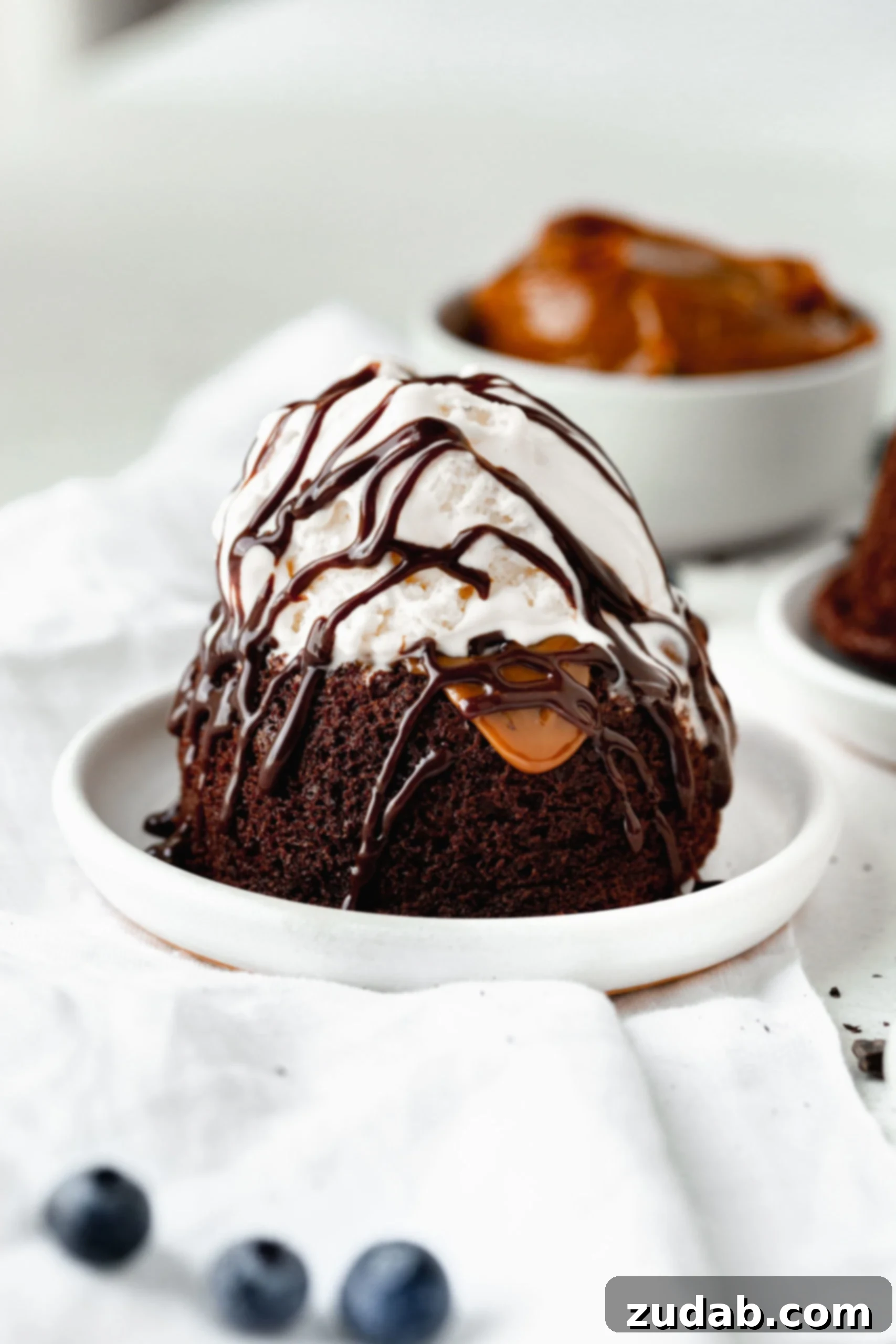 Chocolate Caramel Molten Lava Cakes A molten lava cake with dulce de leche caramel filling. You can see the chocolate cake with the caramel filling oozing out. It is topped with ice cream and drizzles of chocolate.