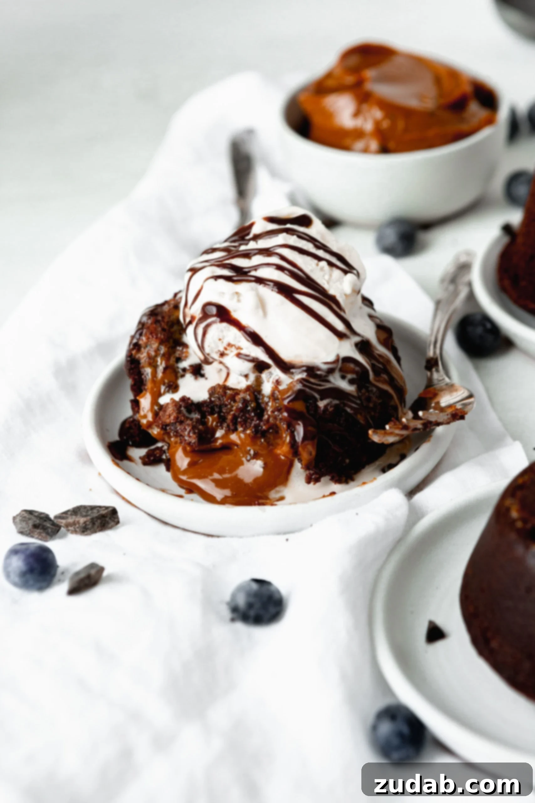 Chocolate Caramel Molten Lava Cakes A chocolate molten lava cake with dulce de leche caramel filling. The chocolate cake has caramel filling oozing out and a scoop of ice cream drizzled with chocolate syrup is on top.